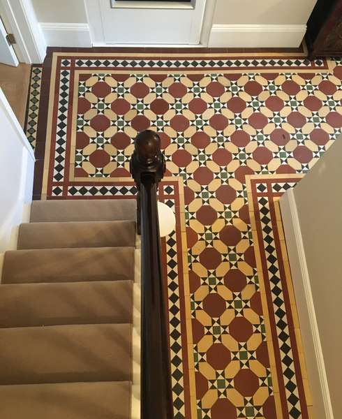 View from above of stairs and a red and yellow mosaic tiled floor