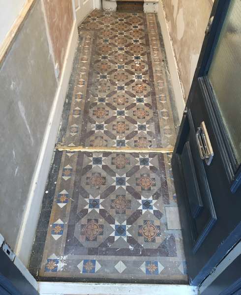 Hallway of a London home with broken and dirty Victorian geometric tiled floor